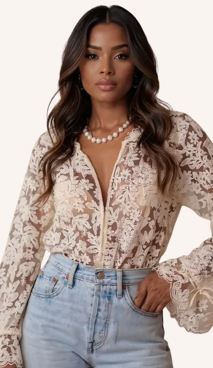 Woman in sheer floral lace blouse and light blue jeans, wearing a pearl necklace