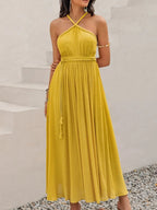 Model wearing a Mustard Yellow Swiss Dot Maxi Dress with halter neck - Heraki Summer Collection