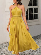Model wearing a Mustard Yellow Swiss Dot Maxi Dress with halter neck - Heraki Summer Collection